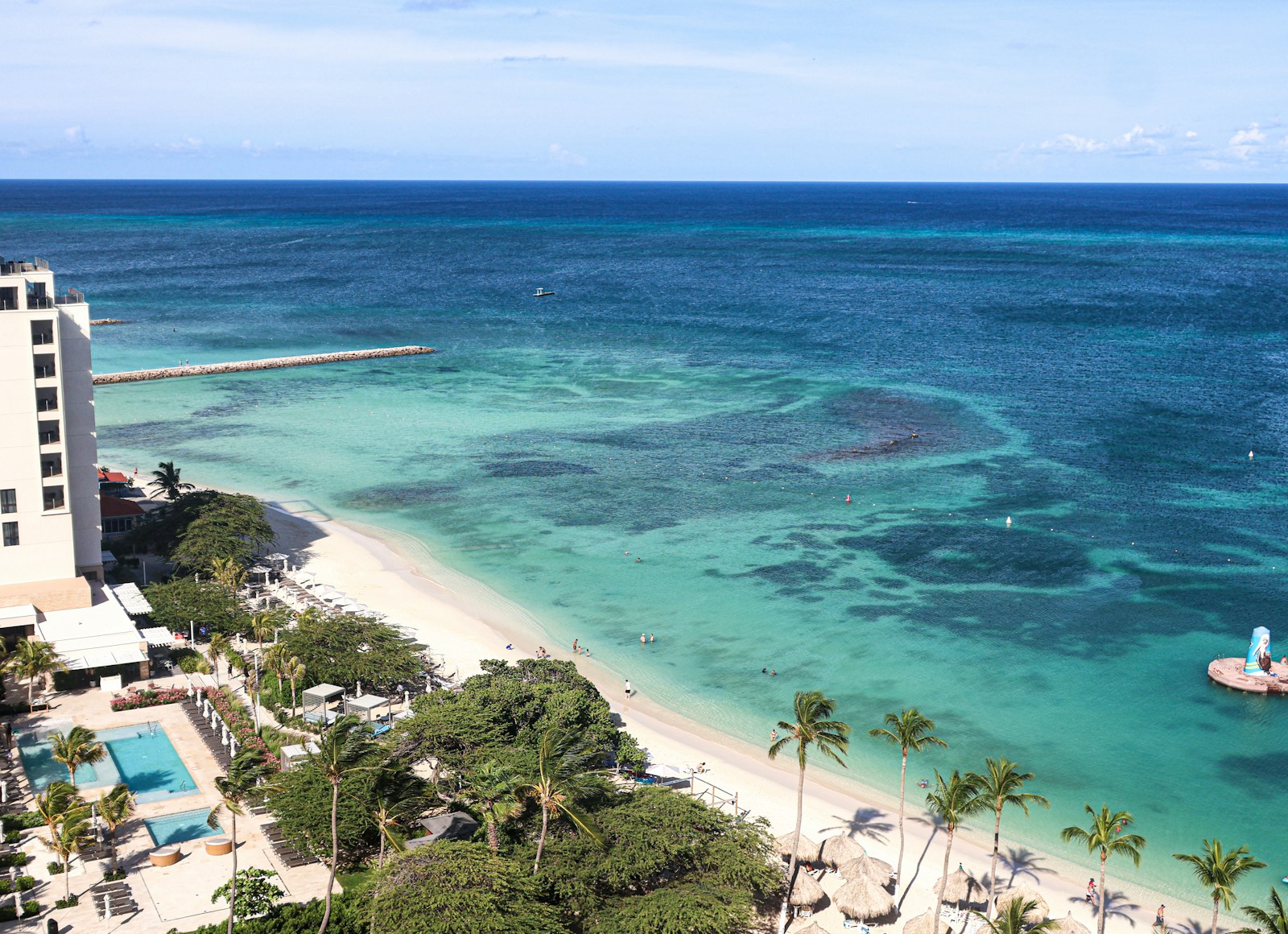 A turquoise resort beach with palm trees and a white-sand shoreline